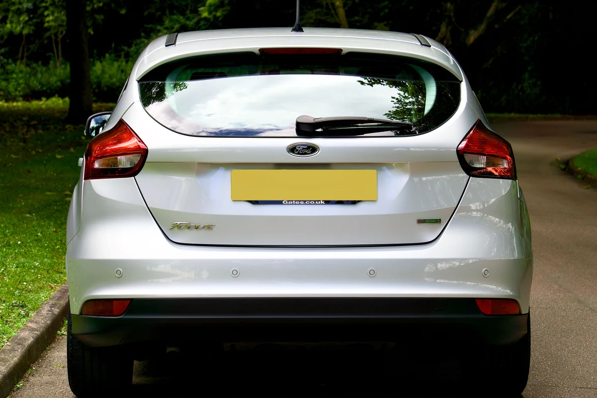Gepflegter silberner Ford Focus in Heckansicht auf einer ruhigen Straße im Grünen