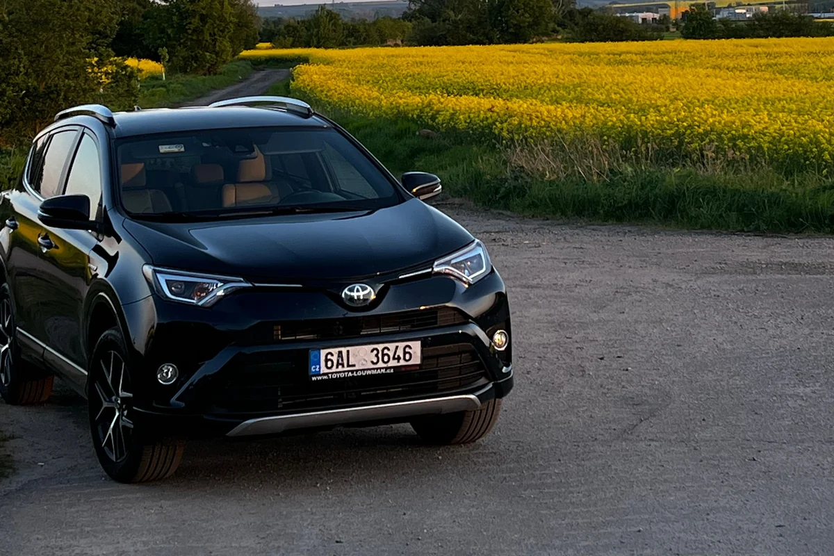 Schwarzer Toyota RAV4 in Dreiviertelansicht an einem ruhigen Feldweg