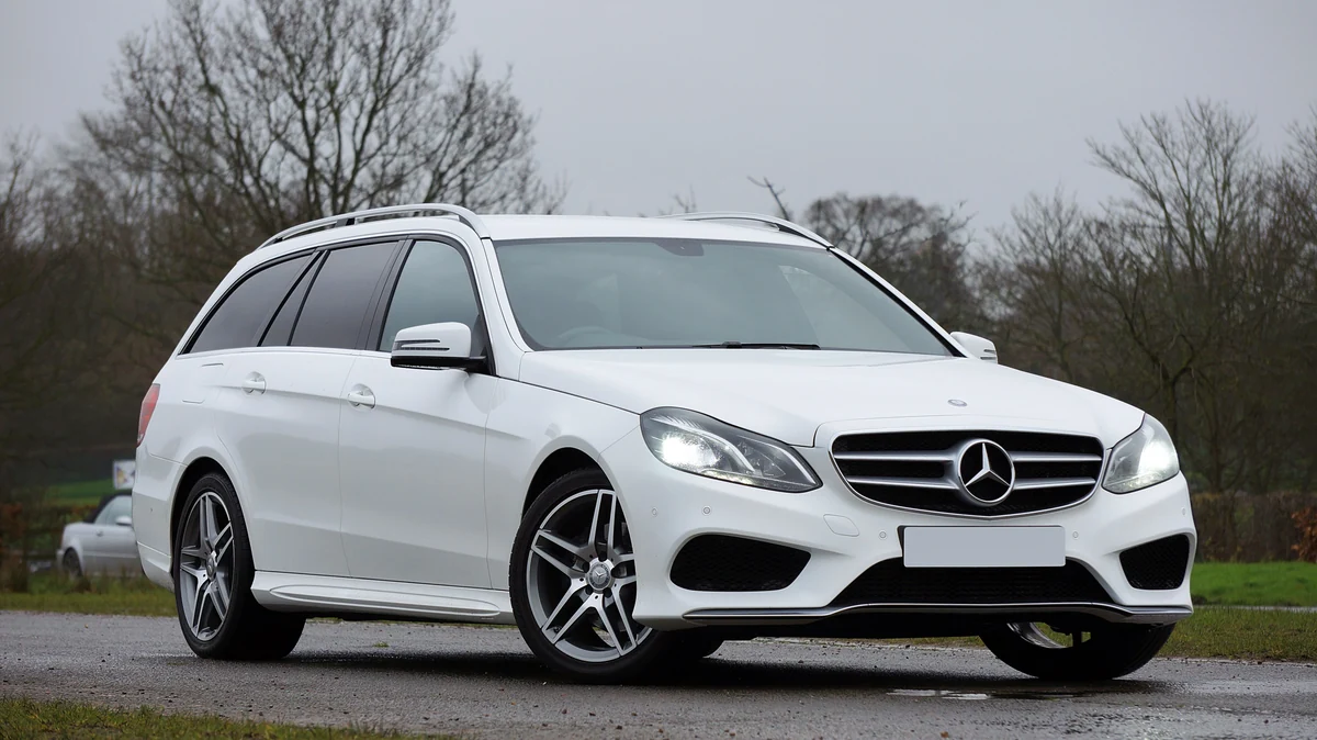 Gepflegter weißer Mercedes-Benz E-Klasse Kombi auf einer ruhigen Straße im Grünen