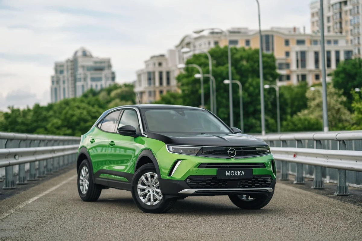 Moderner grüner Opel Mokka mit schwarzem Dach auf einer städtischen Brücke