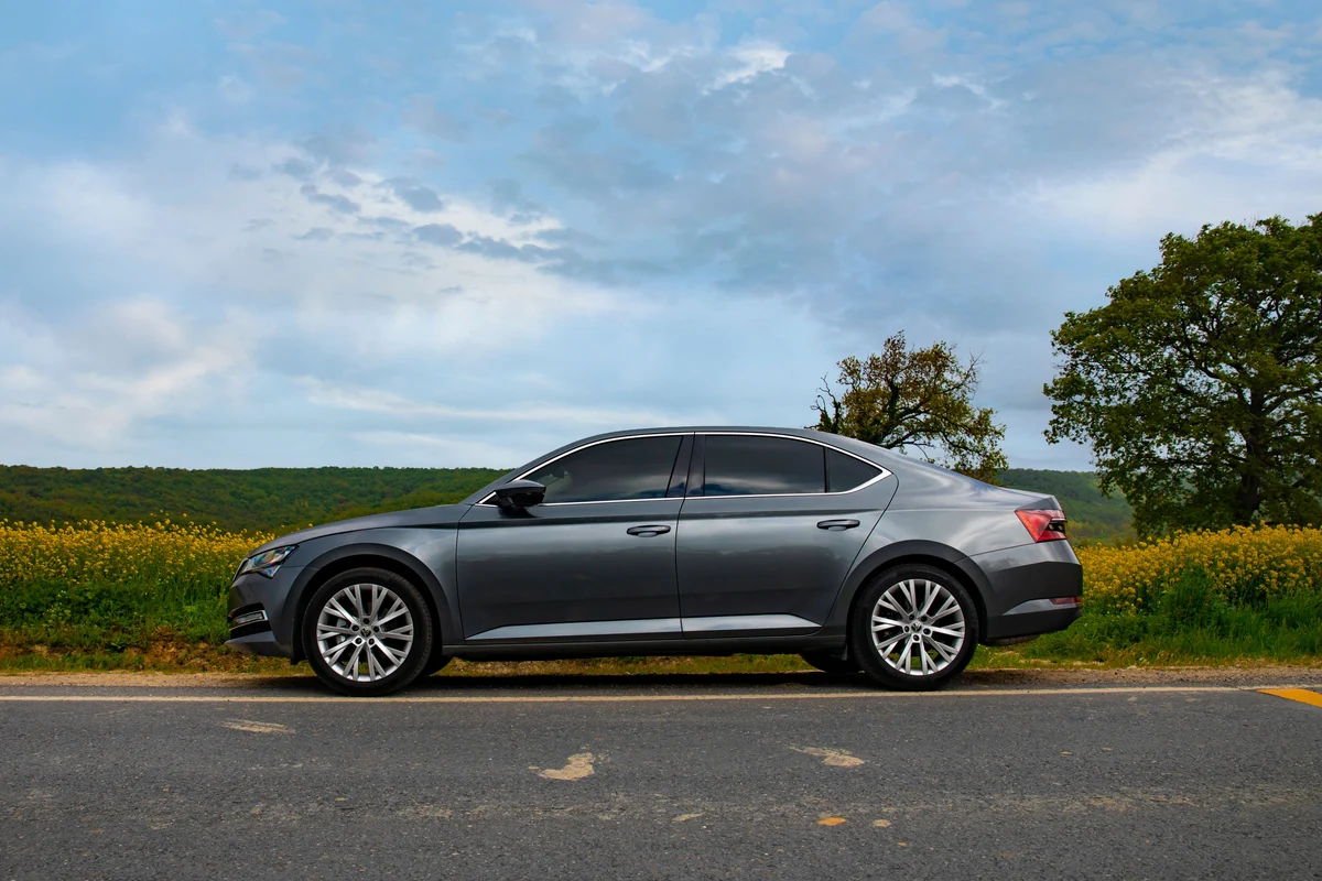 Grauer Škoda Superb in Seitenansicht auf einer ruhigen Landstraße