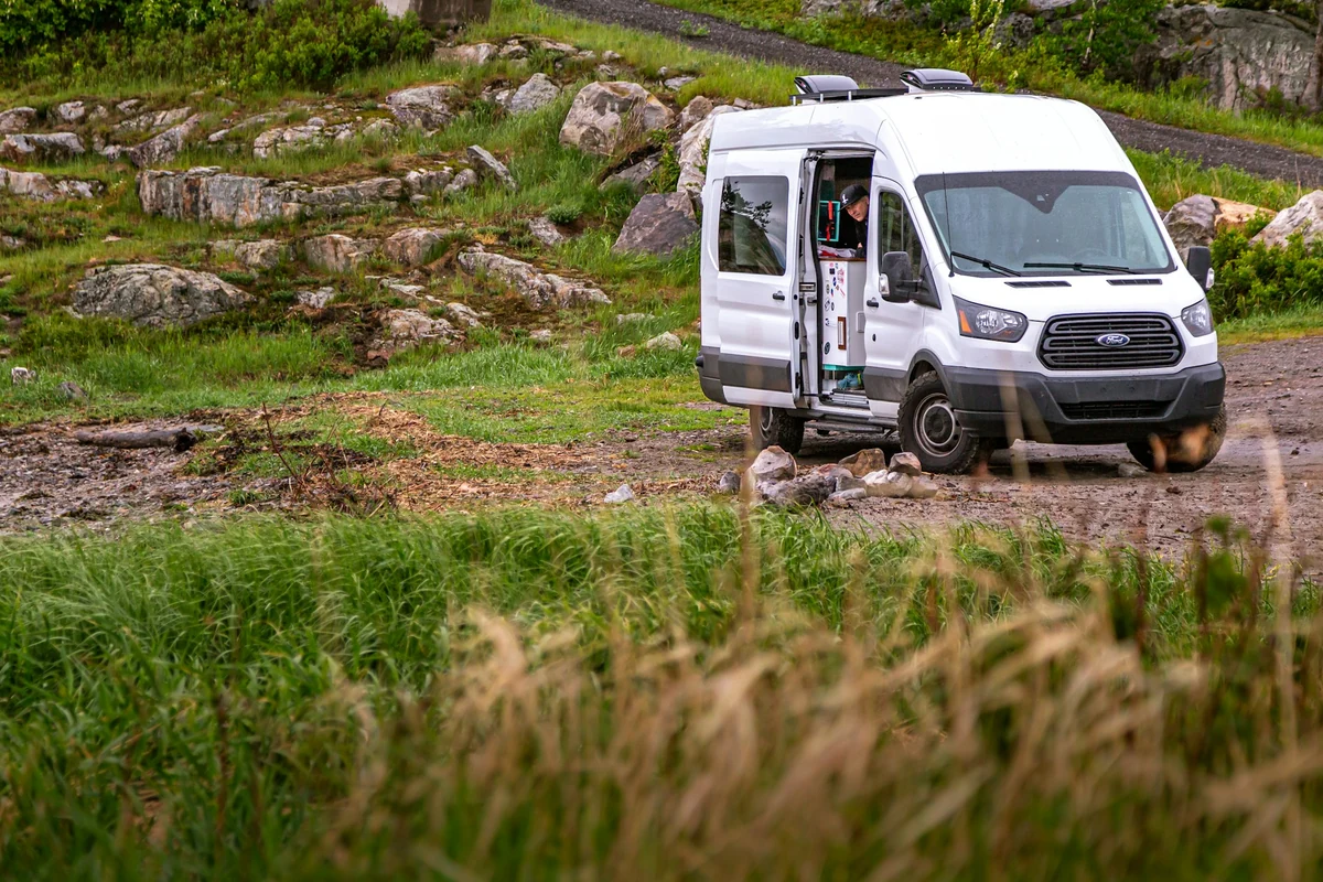 Moderner weißer Ford-Camper mit geöffneter Seitentür in grüner Landschaft