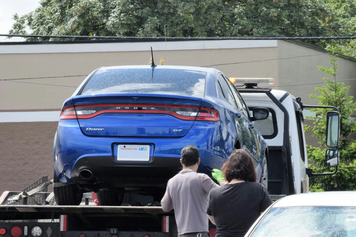 Blauer Pkw auf der Ladefläche eines Abschleppwagens bei der Fahrzeugabholung