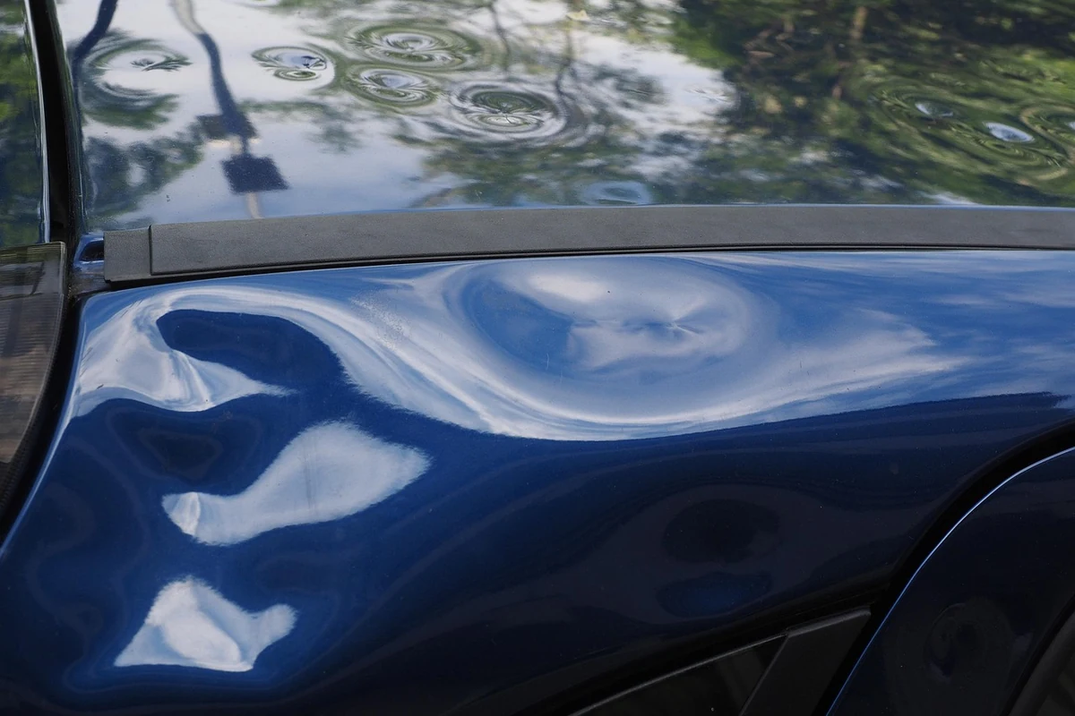 Deutliche Hageldellen im blauen Fahrzeugblech