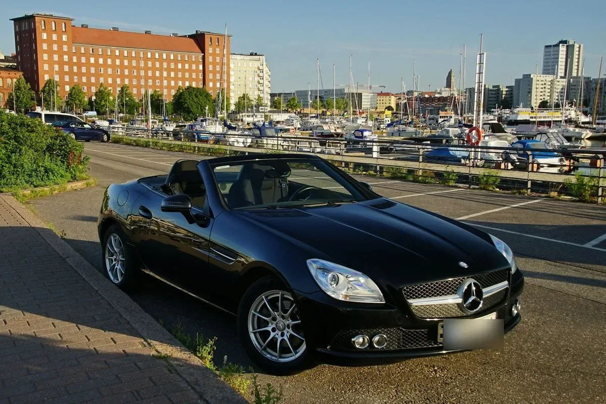 Dunkles Cabrio mit geöffnetem Dach an einem Straßenrand