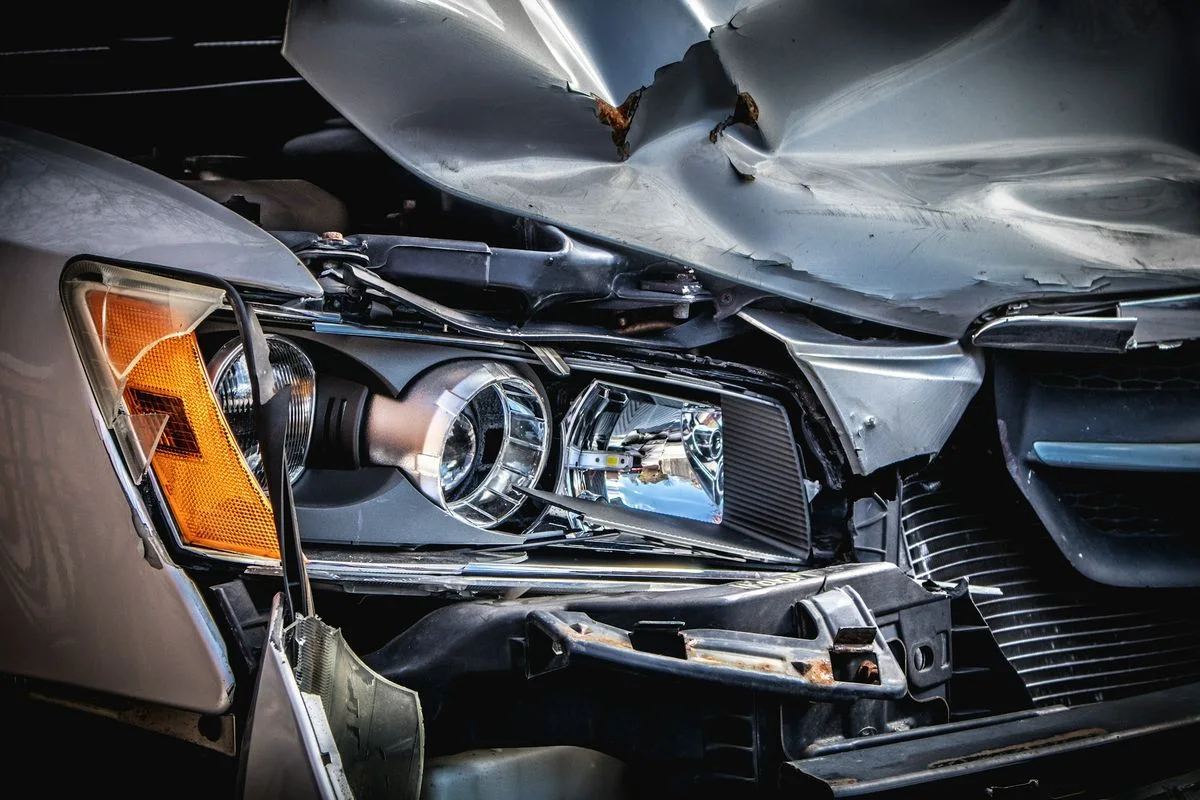 Detailaufnahme eines Pkw mit beschädigter Motorhaube und Scheinwerfer