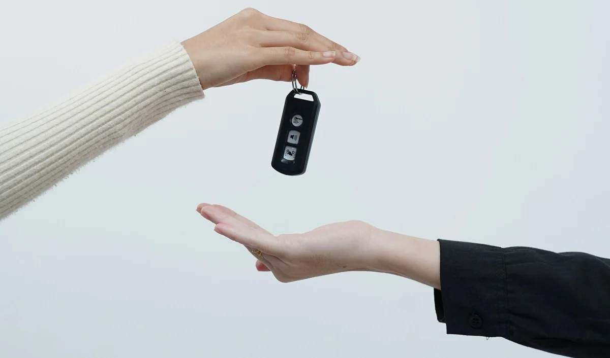 Zwei Hände bei der Übergabe eines neutralen Autoschlüssels